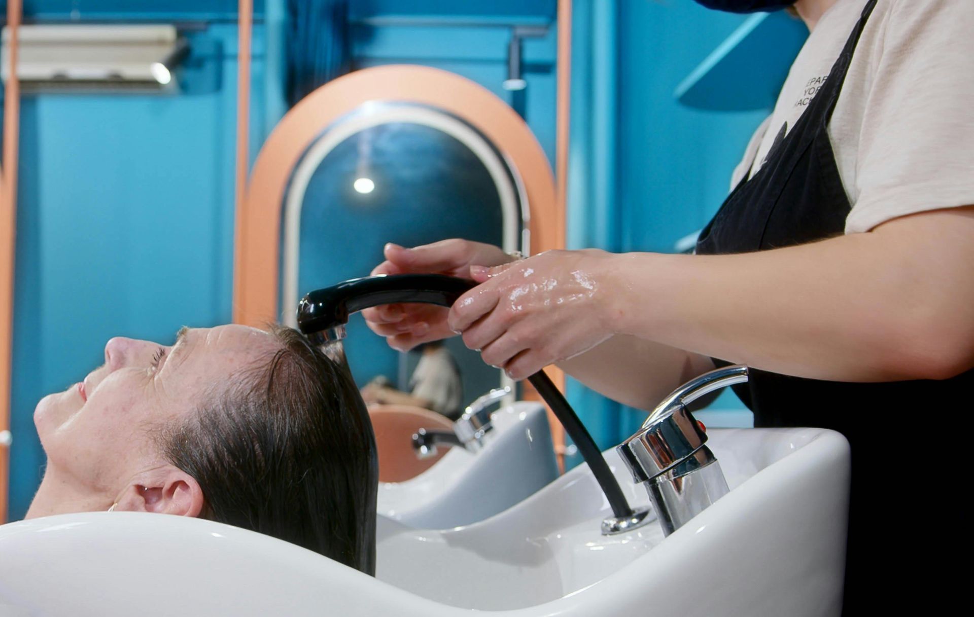 A senior woman gets a relaxing hair wash at a vibrant, modern salon setting.
