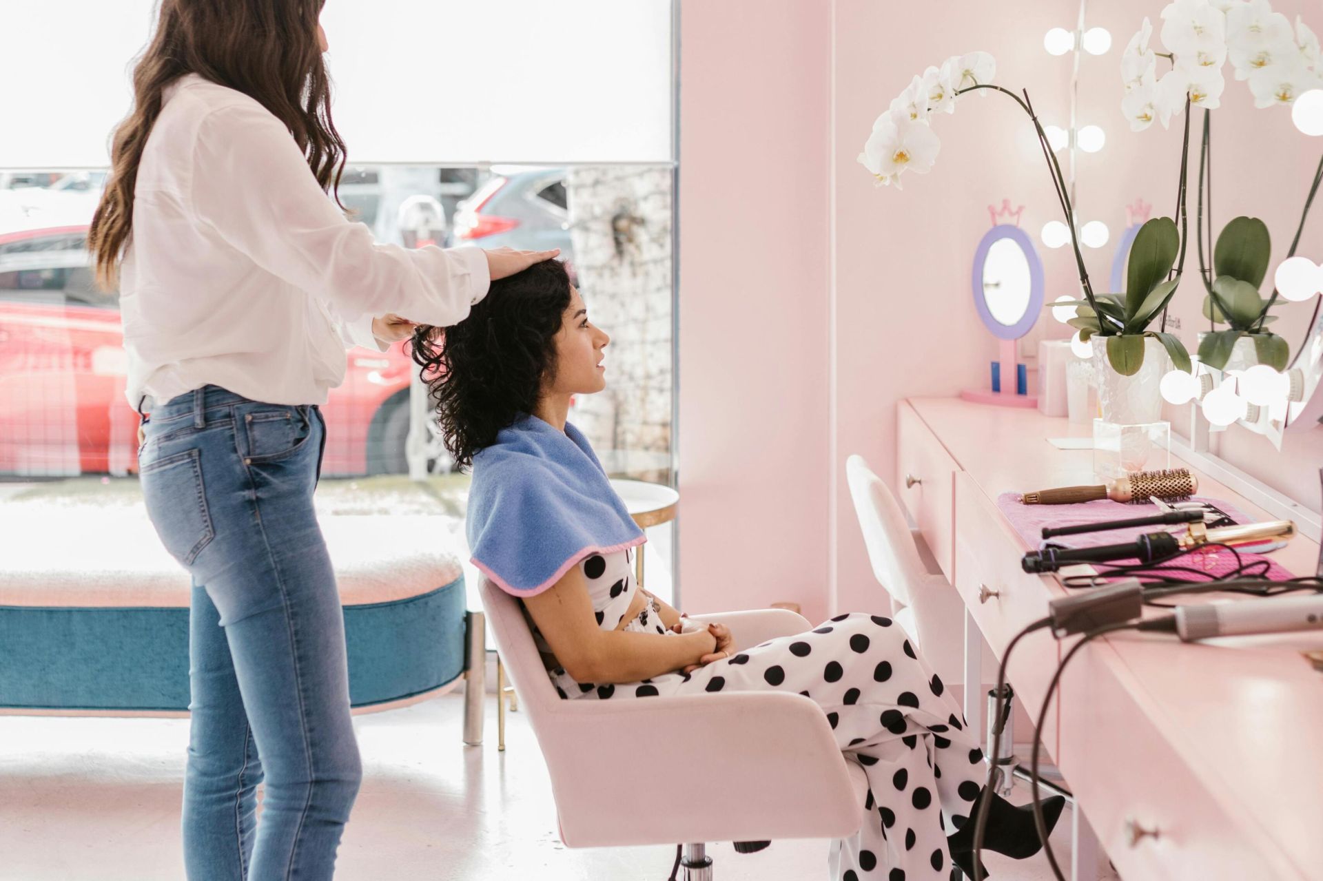 Hairdresser styling client's hair in a modern salon setting with soft lighting.