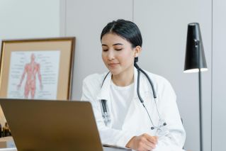 Young female doctor with stethoscope consulting online from office.
